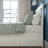 Bed with 4 drawers for storage, white wooden frame, and large pillows.