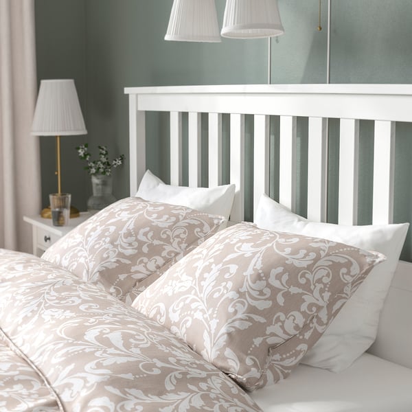 Bed with floral cushions and lamps on both sides.