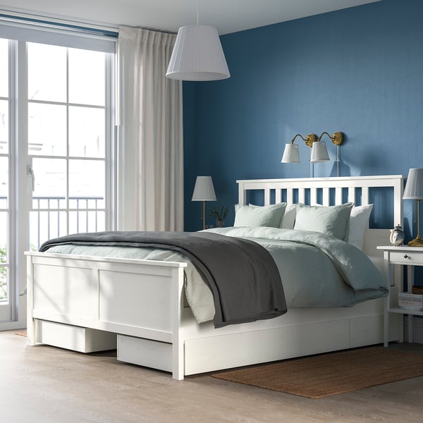 HEMNES bed, white, grey bedding, 4 drawers. By window, blue walls. Grey throw, striped pillows.