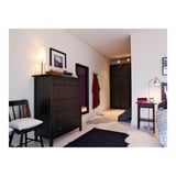 Bedroom with dark wood furniture: chest, chair, wardrobe, rugs, lamp, mirror, and closet.