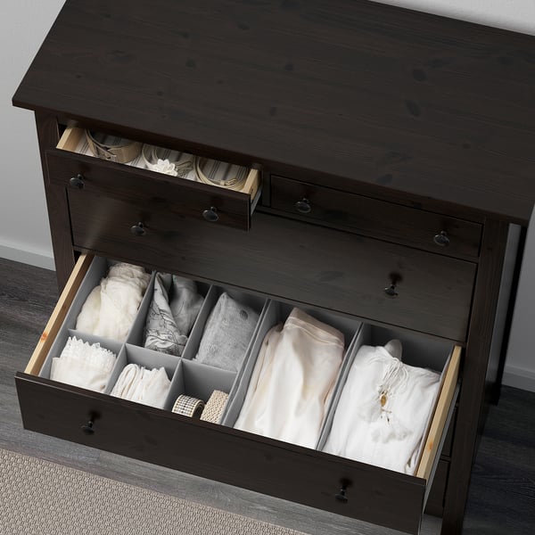 Dark wood chest with open drawers, neatly storing folded clothes. Dividers organize items visually.