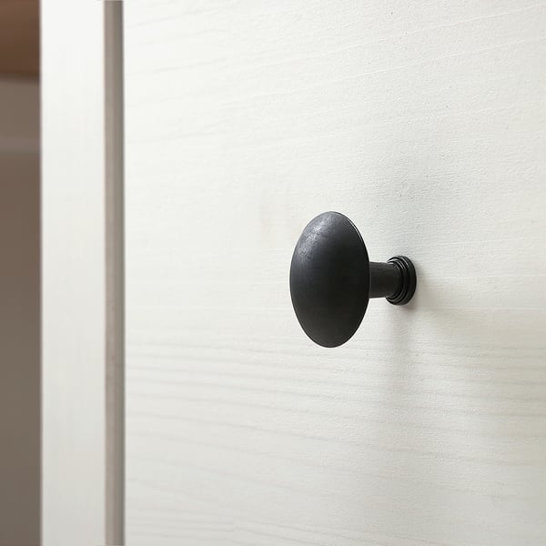 Black round doorknob on smooth white door. Sleek design, quality finish.