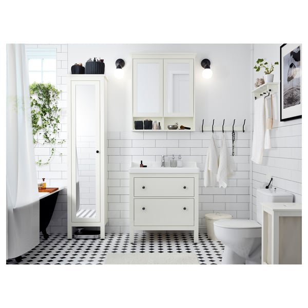 Modern bathroom with white HEMNES vanity, mirror, and cabinets. Black and white tile floor, green plants, and hanging towels. Clean, organized design.