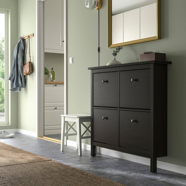 Black HEMNES shoe cabinet fits 8 pairs, wood under mirror, near entryway.
