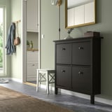 Black HEMNES shoe cabinet fits 8 pairs, wood under mirror, near entryway.