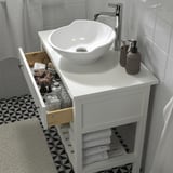 Modern bathroom sink setup. Smooth drawer opens fully, holding toiletries. Underneath, neatly folded towels on shelf.