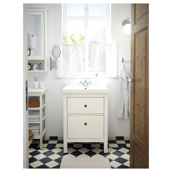 Modern white bathroom with a white HEMNES vanity, black and white checkerboard floor, light grey towels, and a window with sheer curtains.