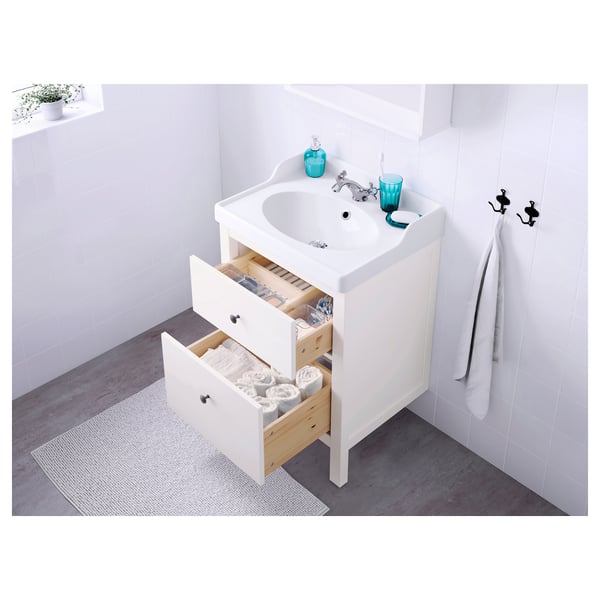 White bathroom vanity with open drawers revealing neatly stacked towels and toiletries. Two handles visible on the wall.