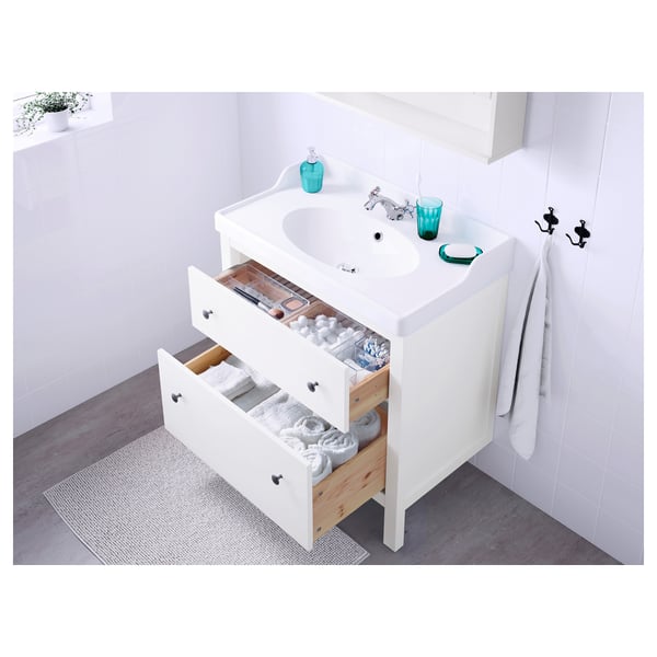 White bathroom vanity with open drawers, sink, and blue glassware.