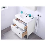 White bathroom vanity with open drawers, sink, and blue glassware.