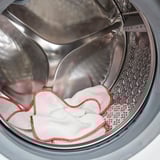 A silver drum washing machine with white towels and red trim inside, ready for a wash.