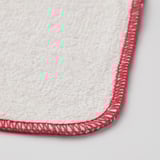 Close-up of a soft, white dishcloth with red trim, highlighting its texture and stitching.