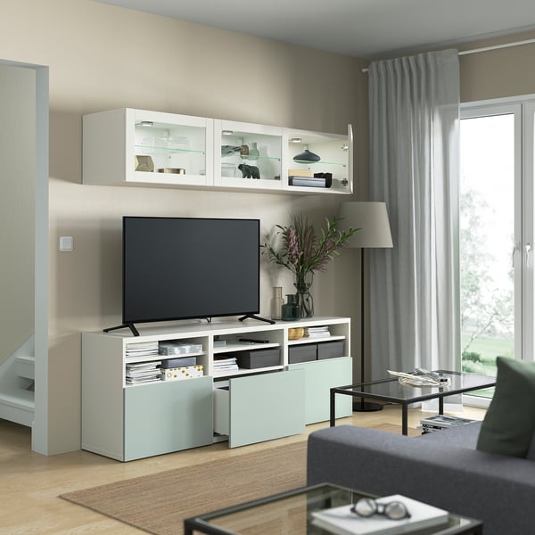 Modern living room with tv cabinet, flowers, lamp, and large window. The HJORTVIKEN storage units offer hidden storage with dust-resistant doors.