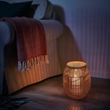 Cozy living room with HÖVISK bamboo lantern near gray chair, blanket.