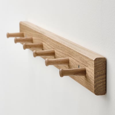 A light brown wooden HÖVOLM coat rack with six knobs for hanging items, featuring a minimalist and simple design.