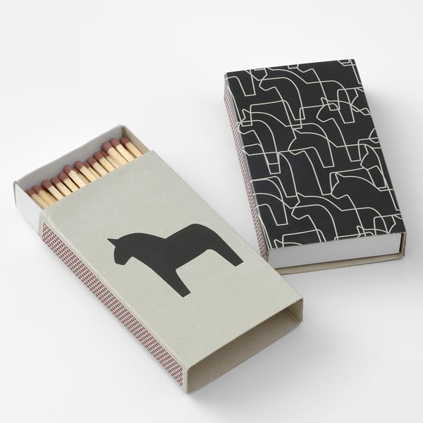 Two rectangular matchboxes, one open showing wooden sticks, both decorated with black silhouettes of dala horses and geometric patterns.