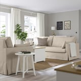 Modern living room with HYLTARP beige sofa, photo frames, white rug, side table, and lamp.