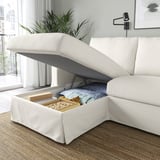 A modern cream sofa with a lift-up chaise longue revealing storage space holding blankets and board games.