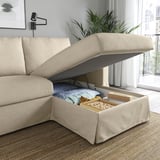 Beige sofa with lift-up chaise longue exposing storage filled with blankets and books.