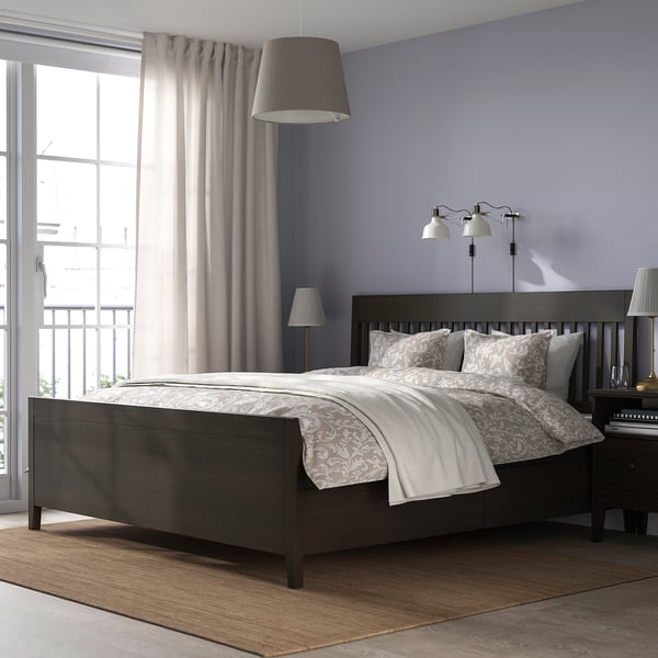 Modern bedroom with IDANÄS dark wood bed, patterned linens, wall lamps, large window, and beige curtains.