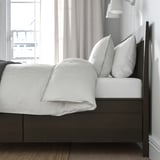 Bed with built-in storage drawers under mattress, soft-closing feature, wooden frame and slatted base.