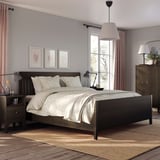 Modern bedroom with IDANÄS dark brown wooden bed, white linens, two nightstands, lamps, and a rug.