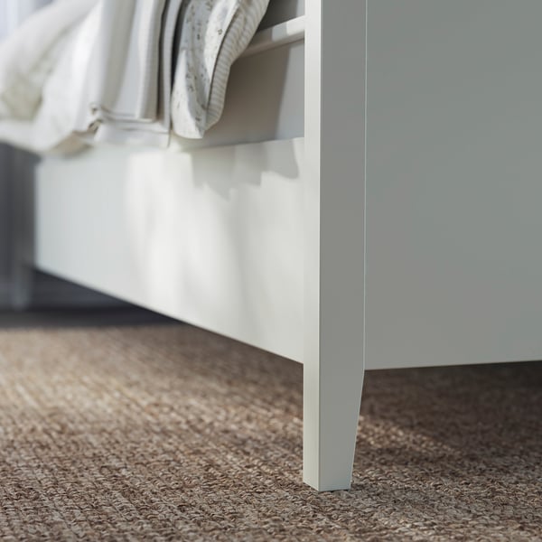White bed frame with drawers, soft-close feature, neatly made, modern design.