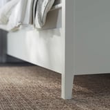 White bed frame with drawers, soft-close feature, neatly made, modern design.