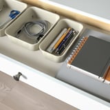 Organized desk drawer with cable management, pens, and notebook.
