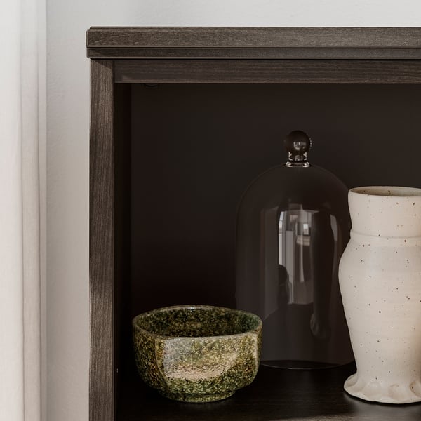Modern dark brown wooden shelf with black glass dome and green, white ceramic bowls.