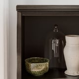 Modern dark brown wooden shelf with black glass dome and green, white ceramic bowls.