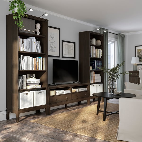Dark wood bookshelves with books & decor, large tv, beige carpet, white couch, black coffee table, grey walls, large window.