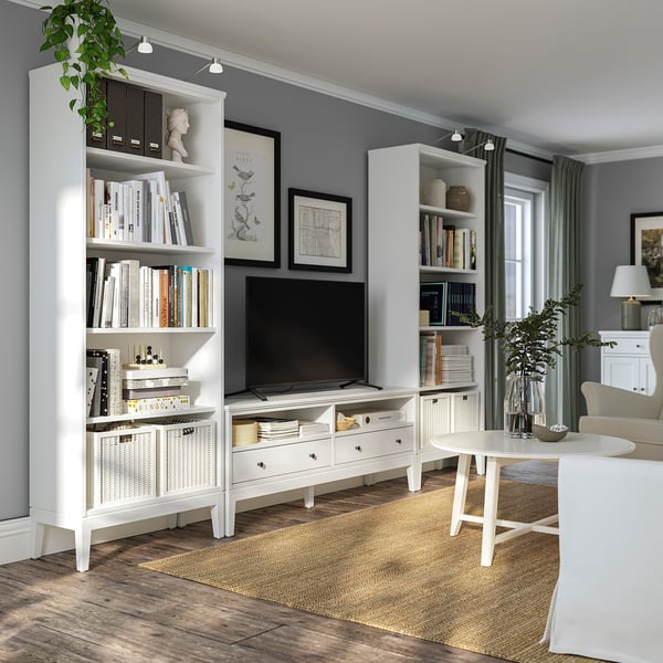 Modern living area with white furniture, grey walls, wooden floors, and many books.