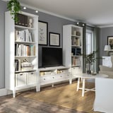 Modern living area with white furniture, grey walls, wooden floors, and many books.