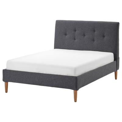 IDANÄS bed: modern grey upholstered frame, sloping headboard, wooden legs.