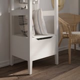 Modern white storage unit with striped pillow, wicker chair beside, on wooden floor.