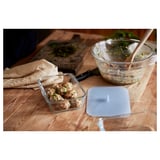 IKEA 365+ glass food container with silicone lid, clear, square, simple design, sits on wooden table with food.