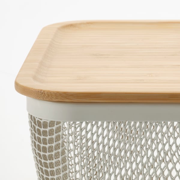 A close-up of a wooden lid with a textured edge placed on a white, diamond-patterned basket.