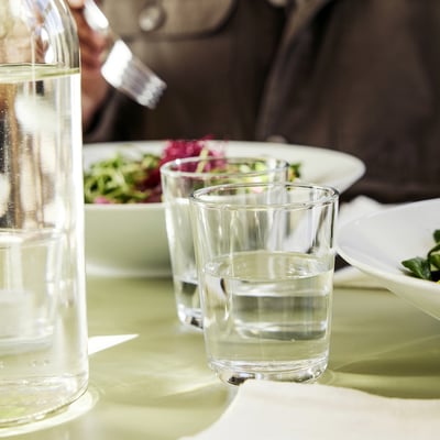 Table set with clear glasses and water pitcher, ready for meal.