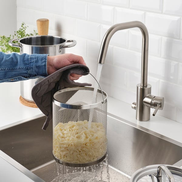 Rinsing food in strainer under faucet.