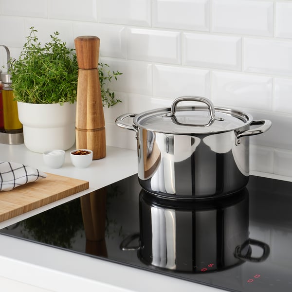 Modern kitchen with induction cooking, mortar, herbs, and towel.