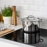 Modern kitchen with induction cooking, mortar, herbs, and towel.