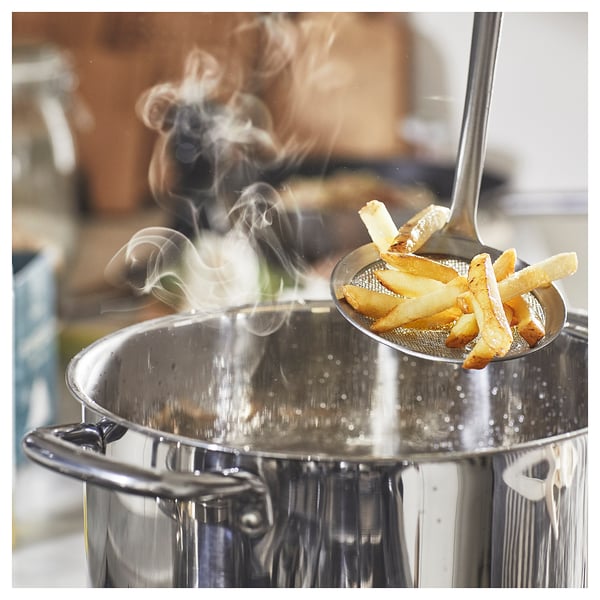 Image a silver frying pan with steam rising and a spoonful of fried food.