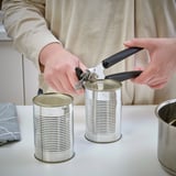 Person opens a can using ikea can opener in kitchen.