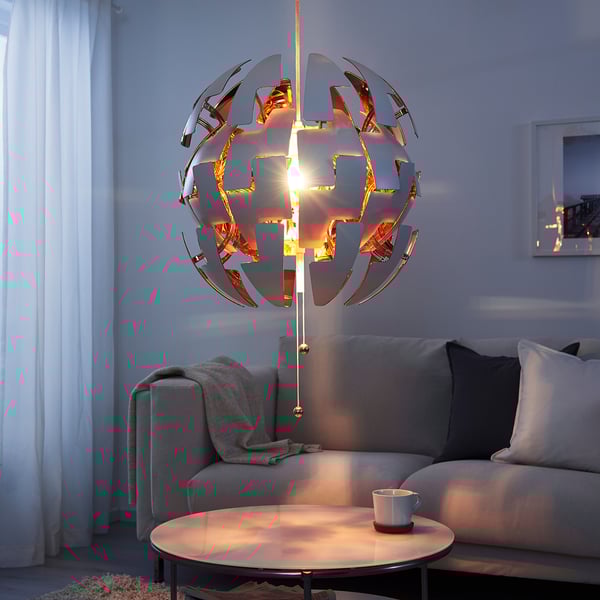 IKEA PS 2014 lamp: futuristic design, metallic finish, spherical. Hangs above coffee table, casts warm light.
