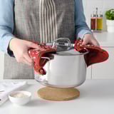 Cook lifts lid with red mitts.