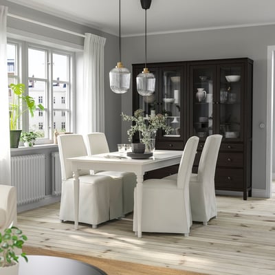 Modern dining room with white INGATORP table and chairs, wooden cabinet, and hanging lamps.