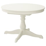 A white round extending dining table named INGATORP. It has a traditional design with a turned leg and can seat 4-6 people with an additional leaf.