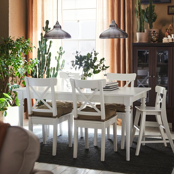Small, white INGATORP dining set with four chairs and extendable table, surrounded by large cacti and pendant lights.