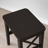 Small, sleek, wooden side table with dark finish and angled legs. Positioned on light, wooden flooring.
